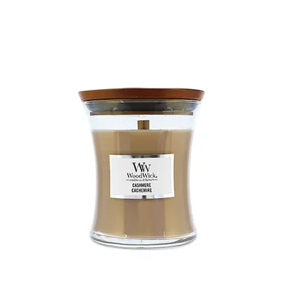A WoodWick candle in a glass jar with a wooden lid, set against a white background.