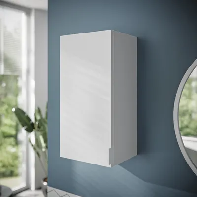 A white bathroom cabinet mounted on a blue wall, with a window and plants visible in the background.