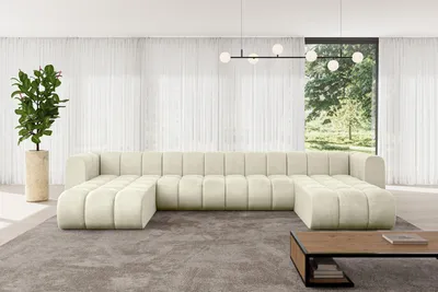 A spacious living room with a large U-shaped modular sofa, a potted plant, and a coffee table.