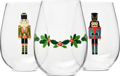 Three clear stemless wine glasses with Christmas-themed nutcracker and holly designs.