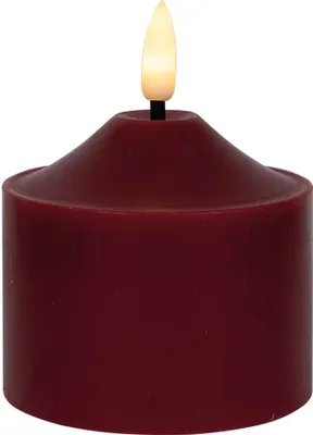 A close-up studio shot of a red LED candle with a warm white flame.