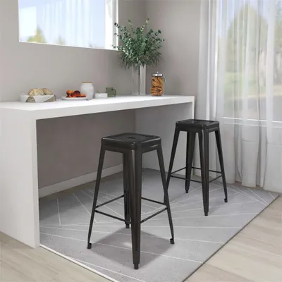 Two black metal bar stools are placed under a white counter in a modern kitchen or dining area.
