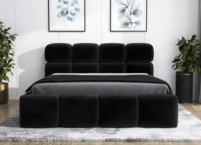 A black upholstered bed with a headboard and a bench in front, set in a bedroom with artwork on the wall and plants.