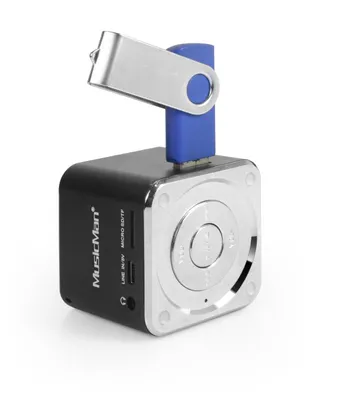 A small black cube-shaped speaker with a silver front panel and a USB drive plugged into the top.