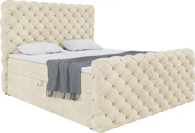 A tufted beige boxspring bed with a mattress and topper, shown from a diagonal angle against a white background.
