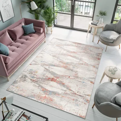 A modern living room with a pink sofa, a patterned rug, and chairs.