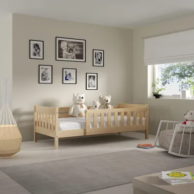 A child's bedroom with a wooden bed, teddy bears, and framed pictures on the wall.