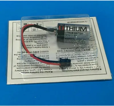 A battery with wires attached, packaged in clear plastic on top of a white and gray paper insert with text.