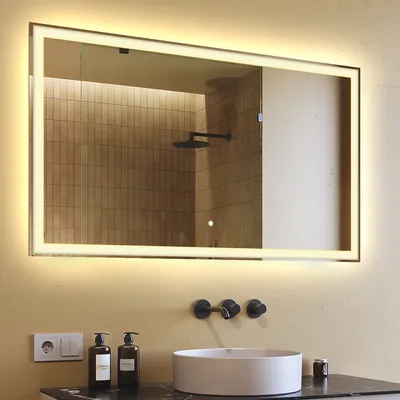 A bathroom scene featuring a large illuminated mirror above a sink.