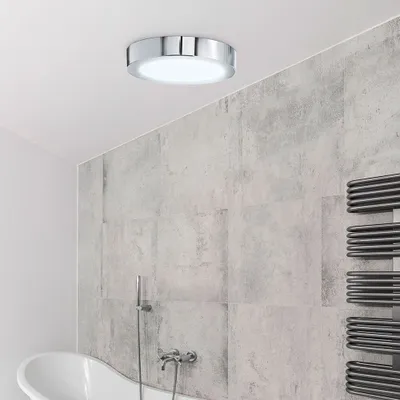 A modern bathroom with a ceiling light, bathtub, and towel rack.
