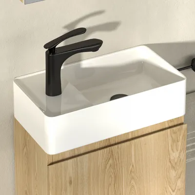 A modern bathroom sink with a black faucet and a wooden cabinet.