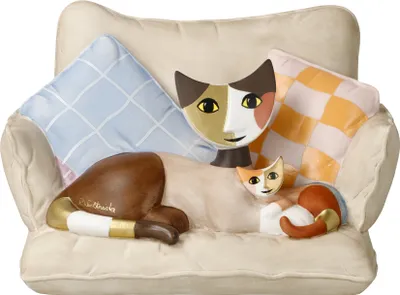 A ceramic figurine of cats on a couch with pillows.