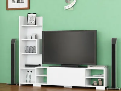A white TV stand with a large black television and two tall black speakers against a light green wall.