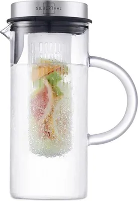 A clear studio shot of a glass pitcher filled with water and fruit.