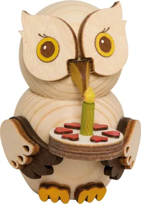 A wooden owl figurine holding a cake with a candle.