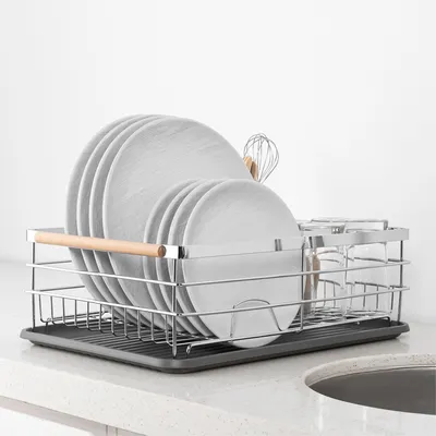 A dish drying rack filled with plates and glasses on a kitchen counter.