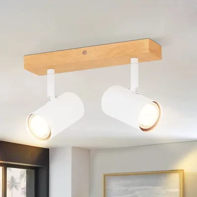 A ceiling light fixture with two adjustable spotlights mounted on a wooden bar, attached to a white ceiling.