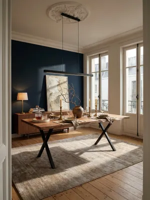 Massiver Akazien-Esstisch mit schwarzen X-Beinen als Mittelpunkt in einem eleganten Esszimmer mit marineblauer Akzentwand und Parkettboden._#sku_SAFWL7.252#