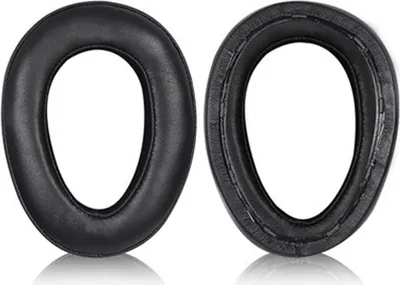 Two black ear pads for headphones are shown side-by-side against a white background. The ear pad on the left is shown from the front, while the ear pad on the right is shown from the back, revealing its internal structure and stitching.