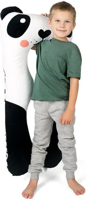 A young boy stands next to a large panda plush toy.