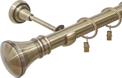 A close-up view of a metal curtain rod with rings and clips, in an antique gold finish.