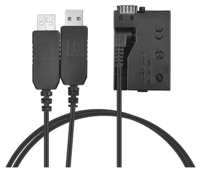 A black camera battery dummy charger kit with two USB cables and a dummy battery adapter.