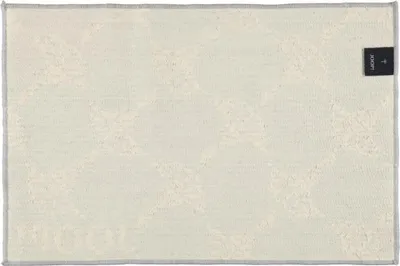 A flat lay of a bath mat with a subtle pattern and a brand tag.