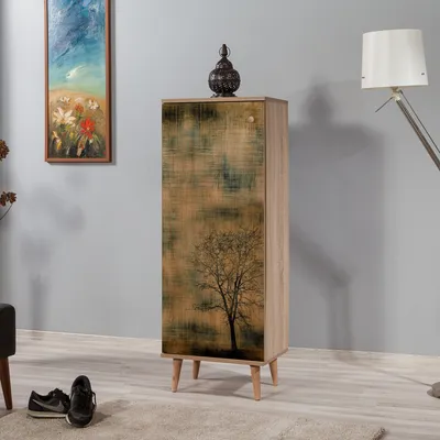 A tall, narrow cabinet with a tree graphic on the door, placed in a room with a painting on the wall and a floor lamp in the background.