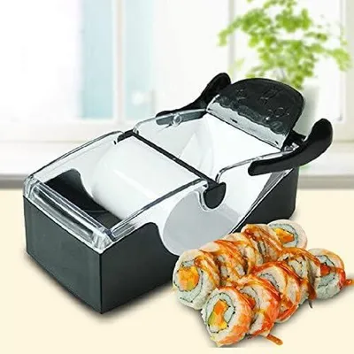A sushi making roller device is shown in the foreground, with a plate of finished sushi rolls in front of it. The background is blurred, showing a window and a plant.
