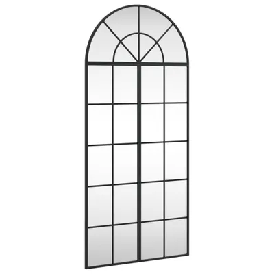 A tall, arched window mirror with a black metal frame, divided into multiple panes.