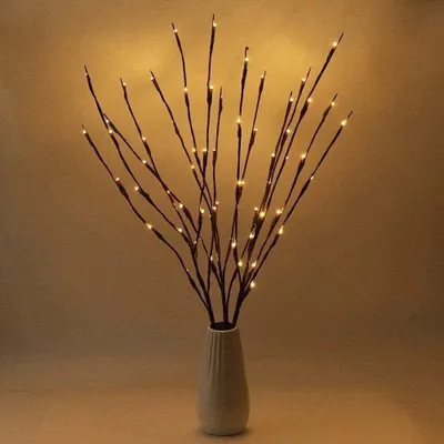 A vase of illuminated branches with warm LED lights.
