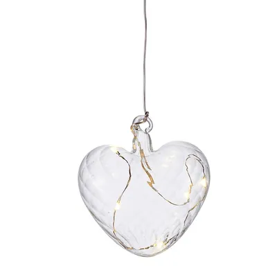 A clear glass heart-shaped ornament with embedded LED lights, hanging from a thin wire.