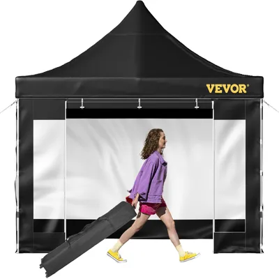 A woman is walking with a rolled-up tent bag in front of a pop-up tent.