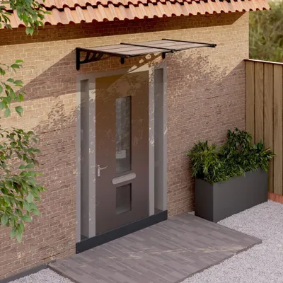 A door canopy is installed above a front door of a brick house.