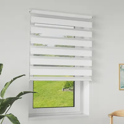 A white zebra blind is installed on a window, with a view of a green lawn outside.