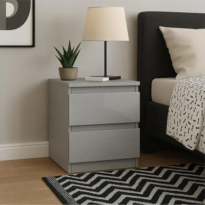 A bedside table with two drawers next to a bed.