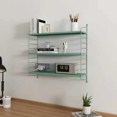 A pastel green modular wall shelf mounted on a white wall, decorated with various items.