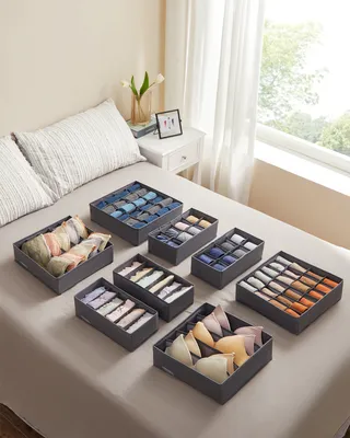 A set of fabric storage organizers filled with undergarments and socks, arranged on a bed.