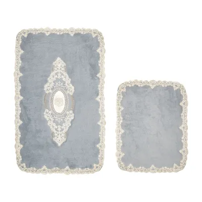 Two bath mats on a white background. The larger mat has an ornate embroidered design in the center.