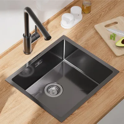 A kitchen sink with a faucet and accessories on a wooden countertop.