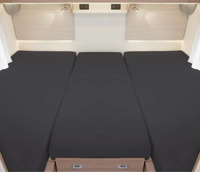Interior view of a camper or caravan showing a three-part bed setup.
