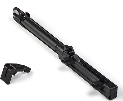 A black mechanical part, likely a component for a cabinet or drawer system, is shown against a white background. A smaller, separate black piece is positioned to the left of the main component.