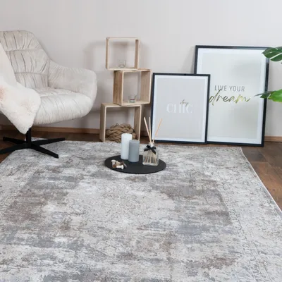 A living room scene with a chair, rug, shelves, and framed art.