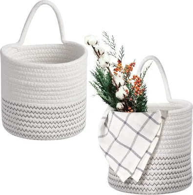 Two woven rope baskets, one empty and one with decorative greenery and cotton stems.
