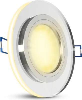 A close-up, angled view of a round, recessed LED ceiling light with a silver reflective trim and a bright yellow light emanating from the center.