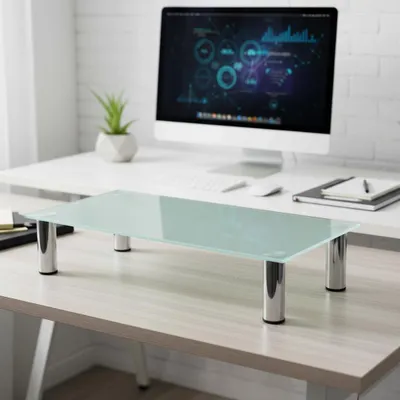 A glass monitor stand is placed on a desk in front of a computer.