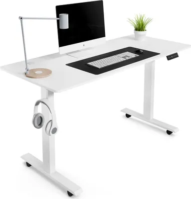 A white adjustable standing desk with a computer, keyboard, mouse, lamp, and headphones.