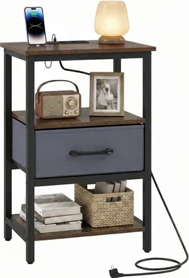 A nightstand with a charging station, a lamp, a radio, and a framed photo.