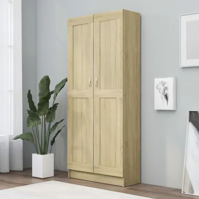 A tall, light brown wooden cabinet with two doors is shown in a room with a plant and artwork on the wall.
