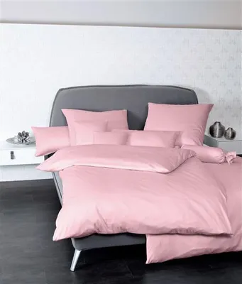 A neatly made bed with pink bedding in a bedroom setting.